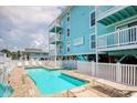 The turquoise condo has a beautiful pool surrounded by a brick patio with lounge chairs and a white privacy fence at 212 58Th Ave. N # 1C, North Myrtle Beach, SC 29582