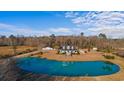 Stunning aerial view of a two-story home with a large pond, fountain, manicured lawn and lush trees at 2325 Highway 111, Little River, SC 29566