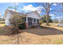 Side view of a quaint single story home with a screened porch and mature trees on a sunny day at 5092 Harrelson Ave., Loris, SC 29569