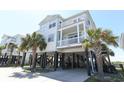 Attractive stilted beach home with multiple covered decks and lush palm trees creating a relaxing tropical vibe at 225-B Dogwood Dr. N, Murrells Inlet, SC 29576