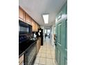 Galley style kitchen with black appliances and wood cabinets that opens to the dining and living room at 2710 N Ocean Blvd. # 1038, Myrtle Beach, SC 29577
