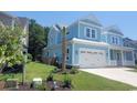 Side view of a two-story blue home with a two-car garage, showcasing its well-maintained lawn at 5023 Middleton View Dr., Myrtle Beach, SC 29579