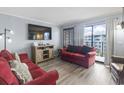 Cozy living room with red couches, wood floors, and balcony access at 5905 S Kings Highway # 416-A, Myrtle Beach, SC 29575