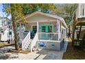 Inviting beach cottage featuring a charming front porch adorned with coastal decor and a vibrant turquoise door at 6001- 1222 S Kings Highway, Myrtle Beach, SC 29575