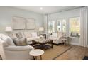 Cozy living room showcasing neutral sofas, armchairs, wood floors, a jute rug, and natural light from expansive windows at 1509 Seachase Way, North Myrtle Beach, SC 29582