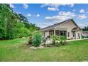 Large backyard featuring a well-maintained lawn, lush landscaping, and a screened porch at 196 Rose Water Loop, Myrtle Beach, SC 29588