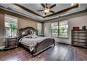 Spacious bedroom with dark wood floors, large windows, and a decorative tray ceiling with a ceiling fan at 2131 Timmerman Rd., Myrtle Beach, SC 29588