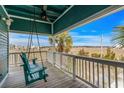 Relaxing porch with a swing offers serene views of the marshland and surrounding neighborhood at 409 25Th Ave. N, North Myrtle Beach, SC 29582