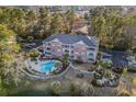 Overhead view of brick condominium community with a swimming pool, parking, mature trees, and pond at 4173 Hibiscus Dr. # 204, Little River, SC 29566