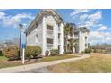 Well-maintained white condo complex featuring multiple stories, balconies and verdant landscaping at 597 Blue River Ct. # H2, Myrtle Beach, SC 29579