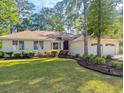 Manicured front lawn showcases a one-story home with an attached two-car garage and mature landscaping at 1043 Yellow Jasmine Dr., Longs, SC 29568