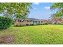 A brick home with a well-maintained yard and mature trees, showcasing its spacious outdoor area at 115 Carolina Ave., Mullins, SC 29574