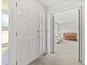 Inviting foyer with a bright white door and a glimpse into the cozy living room with a piano at 115 Carolina Ave., Mullins, SC 29574