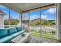 A cozy screened-in porch featuring a blue couch, a white table, and a view of the community pool at 1411 Powhaton Dr., Myrtle Beach, SC 29577