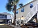 Raised beach house showing stairs, outdoor seating, and proximity to other homes and landscaping at 820 9Th Ave. S, North Myrtle Beach, SC 29582