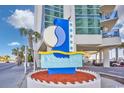 Close up of Oceans One Resort sign in front of the entrance, with tropical palm trees and a blue sky backdrop at 107 S Ocean Blvd. # 1706, Myrtle Beach, SC 29577