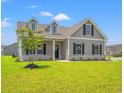 Charming single-story home with gray siding, black shutters, and a beautifully landscaped front yard at 127 Old Chimney Ln, Conway, SC 29526