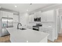 A pristine white kitchen featuring a large island, modern stainless steel appliances and quartz countertops at 1413 Crooked Hook Rd., North Myrtle Beach, SC 29582