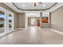 Large living area featuring tile floors, ceiling fan, a tray ceiling, and access to the backyard at 169 Northside Dr., Little River, SC 29566