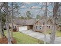 Aerial view of a single-Gathering home with a spacious driveway and well-maintained lawn surrounded by mature trees at 20 Brassie Dr., Carolina Shores, NC 28467