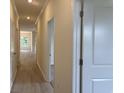 Bright hallway with light wood floors and fresh white walls, leading to various rooms at 264 Palmetto Sand Loop, Conway, SC 29527