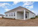 Exterior of home with a covered patio and a view of the backyard with small shrubbery and an empty lot at 4525 East Coast Ln., Shallotte, NC 28470