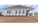 Exterior of home with a covered patio and a view of the backyard with small shrubbery and an empty lot at 4525 East Coast Ln., Shallotte, NC 28470