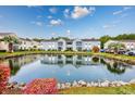 Scenic exterior view of a condo complex with a pond, rocks, and plants with a blue sky overhead at 8861 Cloister Dr. # F, Surfside Beach, SC 29575