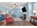 Cozy living room featuring a fireplace, ceiling fan, and hardwood floors at 1186 Pyxie Moss Dr., Little River, SC 29566