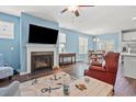Cozy living room with fireplace, ceiling fan, and view of dining area and kitchen at 1186 Pyxie Moss Dr., Little River, SC 29566