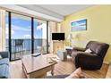 Comfortable living room with a sliding glass door to a balcony with ocean views and a TV at 1210 N Waccamaw Dr. # 1507, Murrells Inlet, SC 29576