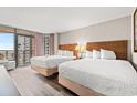 Bright bedroom featuring two queen beds, wood-look floors, and a balcony with ocean views at 1501 S Ocean Blvd. S # 1147, Myrtle Beach, SC 29577