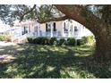 Picturesque home featuring a wraparound porch and lush greenery in the front yard, shaded by a large tree at 213 S Farr Ave., Andrews, SC 29510