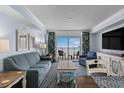 Cozy living room featuring a comfortable blue sofa, stylish decor, and access to a balcony with ocean views at 2201 S Ocean Blvd. # 1707, Myrtle Beach, SC 29577