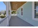 Outdoor covered porch with wood ceiling and white railing, offering a relaxing space with blue siding at 417 Seabreeze Dr., Garden City Beach, SC 29576