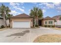 Stucco home featuring palm trees, two-car garage, and well-maintained landscaping at 601 Tradewind Ct., North Myrtle Beach, SC 29582