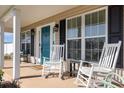 Cozy front porch features rocking chairs, bright blue door, and ample natural light streaming through the windows at 115 Blue Pride Dr., Loris, SC 29569