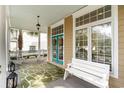 Inviting front porch featuring a bench, rocking chairs, and colorful double doors, perfect for relaxing outdoors at 1523 James Island Ave., North Myrtle Beach, SC 29582