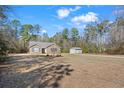 Spacious front yard with an outbuilding on a sunny day, surrounded by lush trees, offering privacy and space at 1580 Circle Bay Dr., Longs, SC 29568