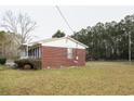 Brick home featuring a side view with a partially covered porch and lawn area at 3285 Della Rd., Longs, SC 29568