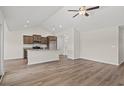 Open-concept living area featuring vaulted ceiling, ceiling fan, wood-look floors, and kitchen with granite countertops at 411 Lifestyle Court, Surfside Beach, SC 29575