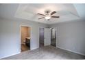 Spacious main bedroom featuring carpet, ceiling fan, tray ceiling, ensuite bath, and a walk-in closet at 411 Lifestyle Court, Surfside Beach, SC 29575