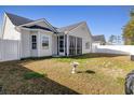 Backyard showcasing well-maintained lawn, screened porch, privacy fence, and lush green grass at 804 Twickenham Loop, Longs, SC 29568