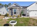 Exterior view of lovely single-story home featuring a stone facade, manicured landscaping, and a charming front porch at 804 Twickenham Loop, Longs, SC 29568