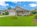 Attractive single-story home with a manicured lawn, attached garage, and welcoming front porch at 441 Plymouth Loop, Longs, SC 29568