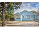 Exterior view of the blue house with a paved area and mature trees at 1019 Prince St., Georgetown, SC 29440