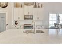Spacious kitchen island featuring a sink and quartz countertops, enhanced by stainless steel appliances and white cabinetry at 1439 Castleberry Pl., Myrtle Beach, SC 29588