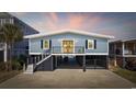 Charming coastal home with a blue exterior, black shutters, and a spacious drive-under garage at 414 S Dogwood Dr., Garden City Beach, SC 29576