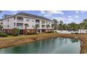 The condo's exterior showcases a serene pond and access to a well-maintained pool at 4142 Hibiscus Dr. # 104, Little River, SC 29566