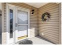 Close-up of a front door with glass features, a wreath, and neutral-colored siding at 4243 Rivergate Ln., Little River, SC 29566